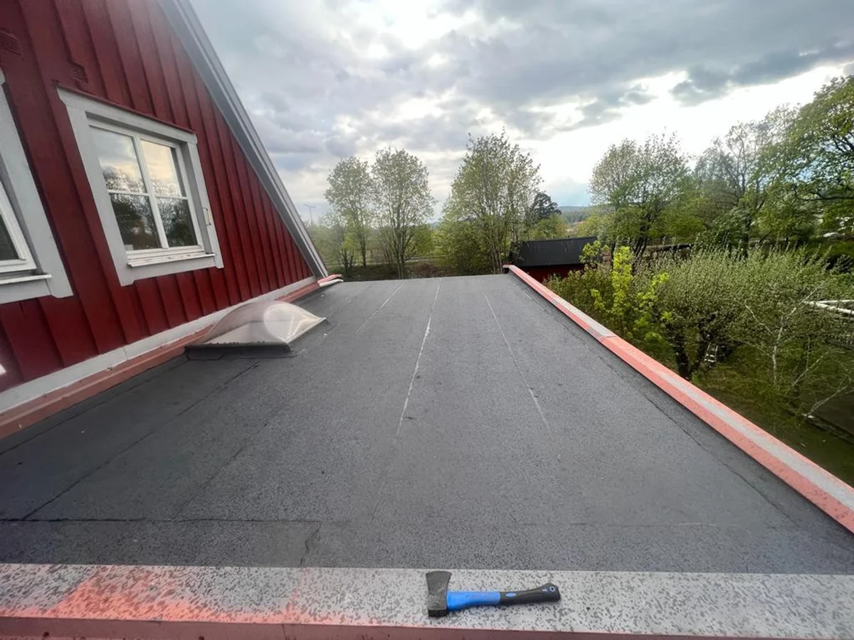 Omlagt papptak på garage vid ett rött hus i Falun.